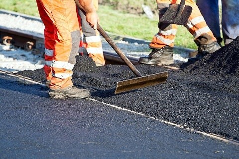 Road construction in operation with  workers paving a road with asphalt
