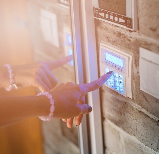 A woman typing a code on an alarm system. 