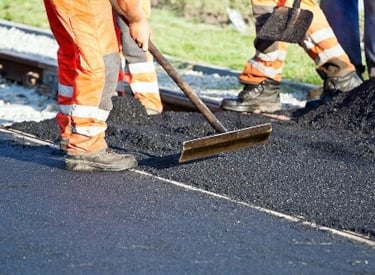 Road construction in operation with workers paving a road with asphalt