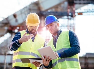 Twee mannen die op de bouwplaats plannen bespreken