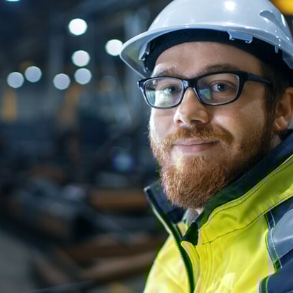 Medewerker met helm die vriendelijke de camera in kijkt
