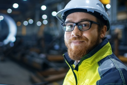 Medewerker met helm die vriendelijke de camera in kijkt